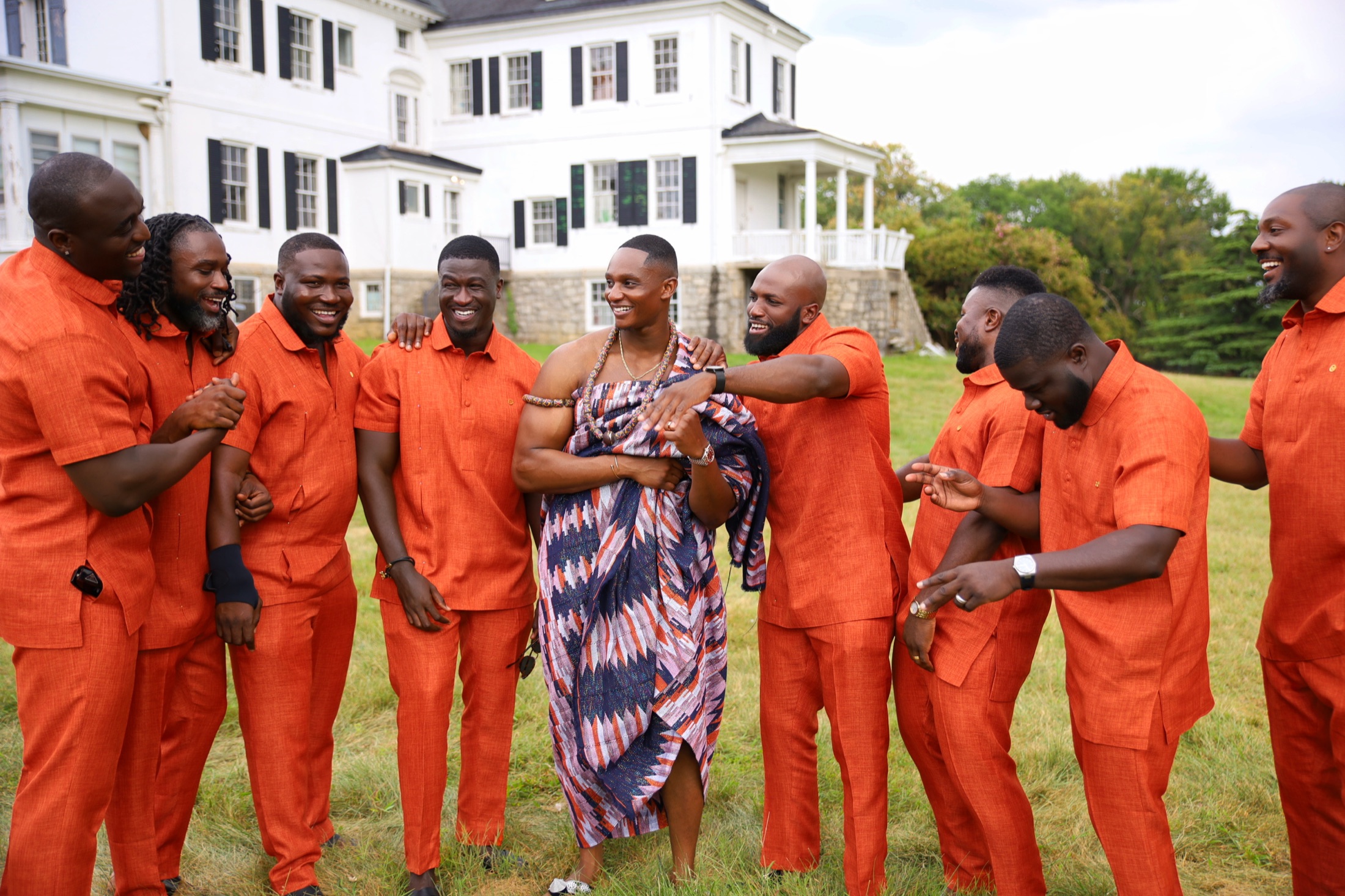 Wedding party laughing together on an estate lawn