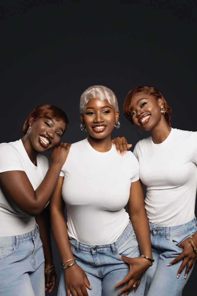 Three women in white tees and jeans posing together