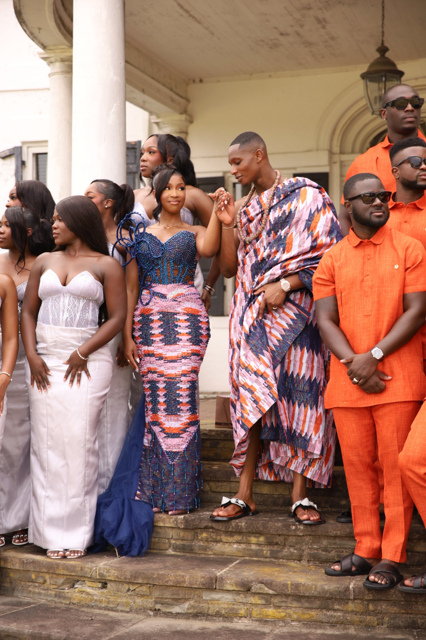 A celebration party in coordinated traditional attire on mansion steps