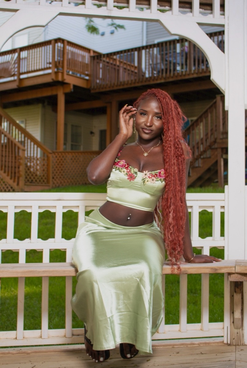 Woman with red hair in a sage green set posing on a farmhouse porch