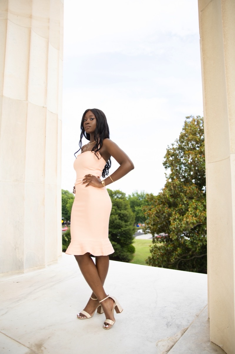 Woman in a peach dress posing between the Lincoln Memorial columns