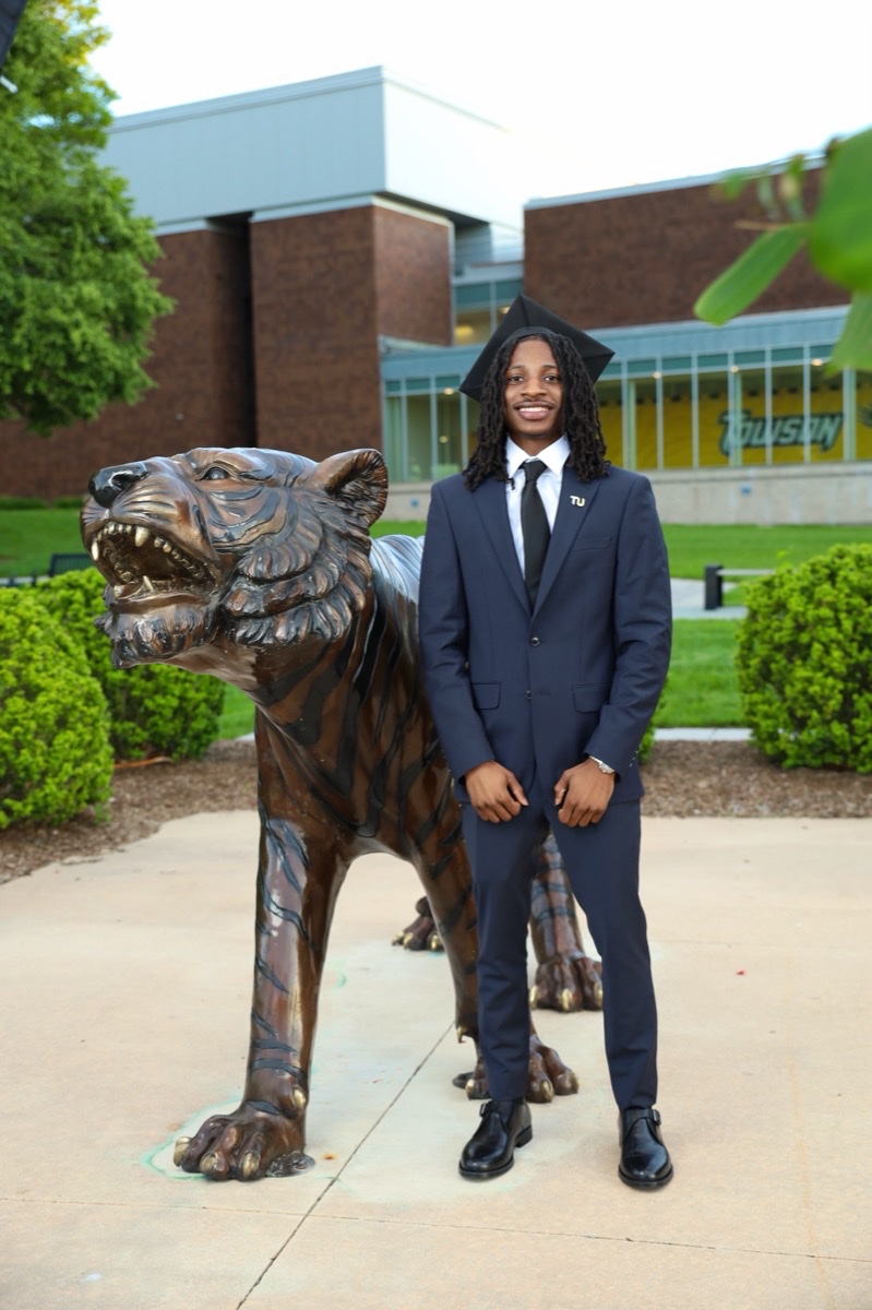 Prom couple posing beside a bronze tiger statue