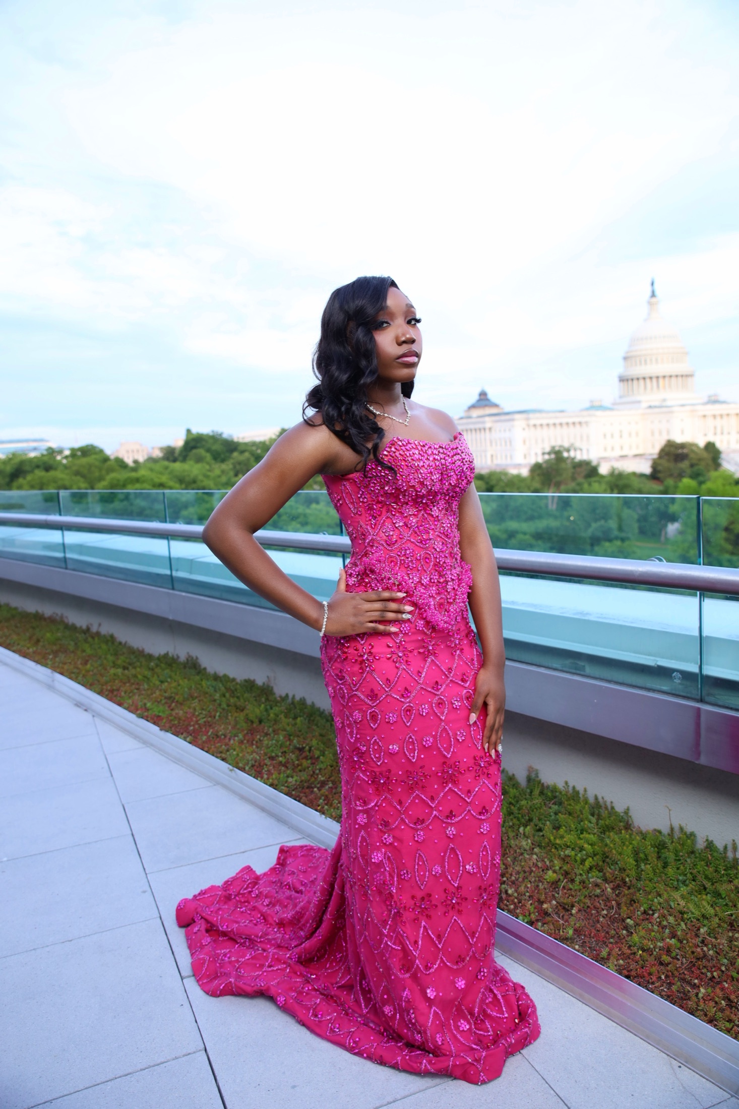Woman in a beaded pink gown on a rooftop overlooking the U.S. Capitol