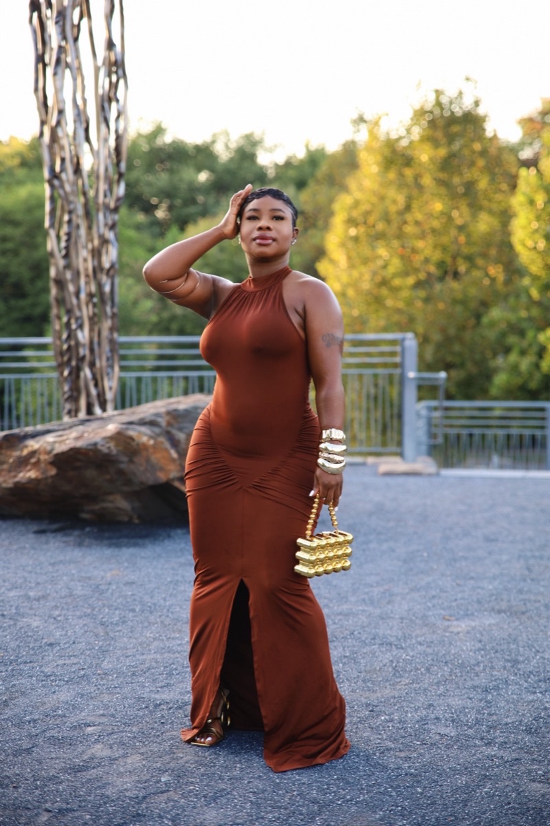 Woman in a rust-colored gown posing in a park at golden hour