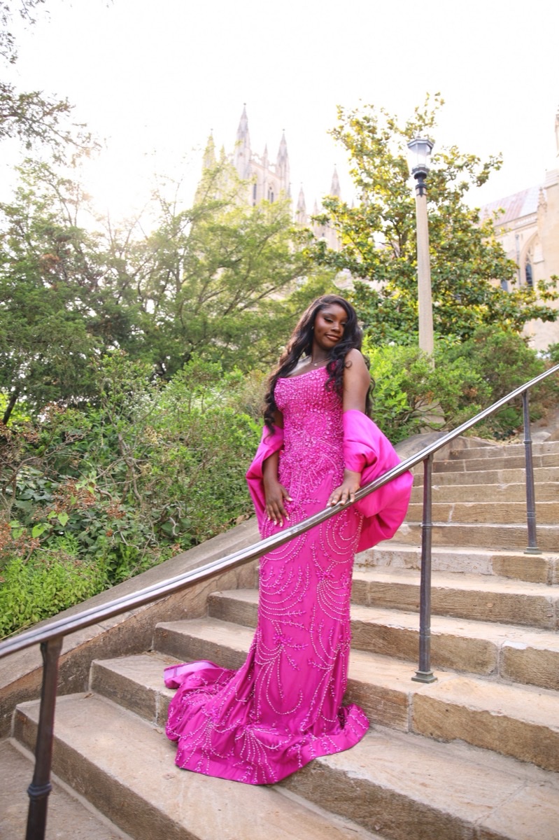 Woman in a hot pink gown posing on a staircase